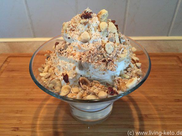 Ein Schälchen knuspriges Keto Nussmüsli mit einer cremigen Mascarpone-Schicht, garniert mit Nüssen und Kokosraspeln.