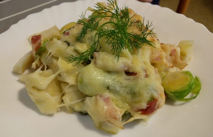 Servierte Portion Rosenkohl-Fenchel-Auflauf auf einem weißen Teller, garniert mit frischem Fenchelkraut.