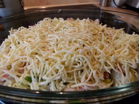 Rosenkohl-Fenchel-Auflauf mit einer großzügigen Schicht geriebenem Gouda, fertig zum Backen im Ofen.  