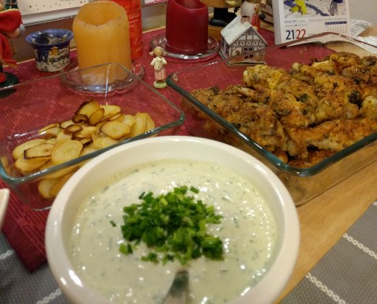 Knusprige, goldbraune Keto Chicken Wings mit würziger Parmesanpanade, angerichtet mit cremigem Käse-Dip und frischen Kräutern auf einem rustikalen Esstisch.