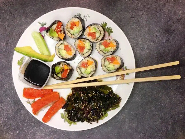 Keto Sushi mit Blumenkohlreis, Avocado, Gurke und Räucherlachs, serviert auf einem Teller – perfekt für die ketogene Ernährung.  