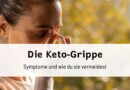 Eine Frau, die sich die Nasenwurzel reibt, als Zeichen von Kopfschmerzen, typisches Symptom der Keto-Grippe, mit Text-Overlay: 'Die Keto-Grippe – Symptome und wie du sie vermeidest