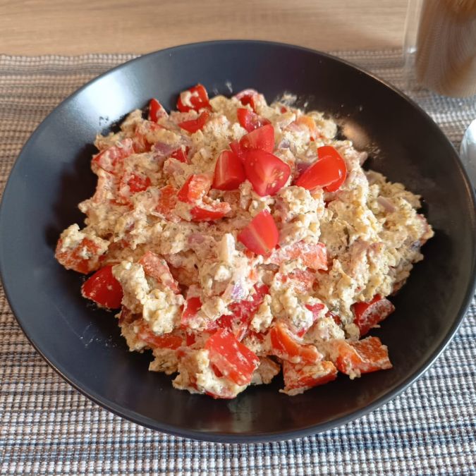 Eine Schale mit cremigem Keto-Rührei mit Frischkäse, Bacon, Paprika und Tomaten